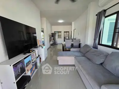 Spacious living room with modern decor and large TV, perfect for relaxation.