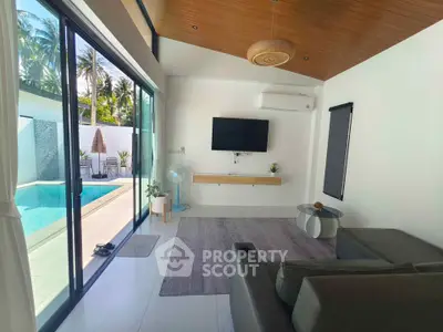 Modern living room with pool view, sleek furniture, and large glass doors opening to a tropical paradise.