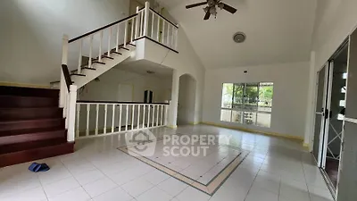 Spacious open-plan living room with high ceiling and staircase