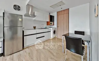 Modern kitchen with sleek appliances and dining area in open layout apartment.