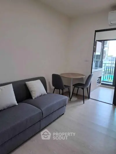 Modern living room with gray sofa and dining set, featuring a balcony view.