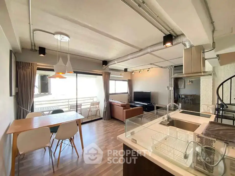 Spacious modern living room with open kitchen and dining area, featuring large windows and stylish decor.
