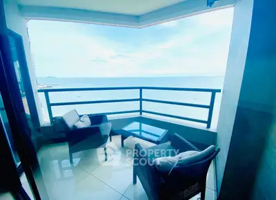 Stunning ocean view from a modern balcony with cozy seating area, perfect for relaxation.
