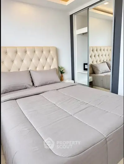 Luxurious bedroom with plush headboard and mirrored wardrobe, perfect for modern living.