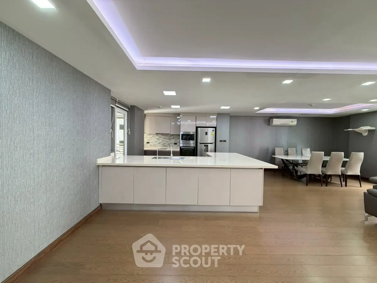Spacious modern kitchen with open layout and dining area, featuring sleek design and ample lighting.