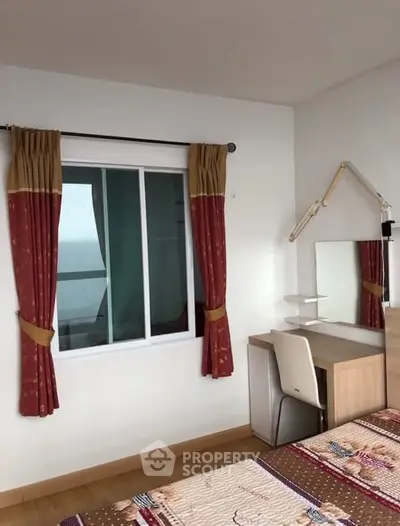 Cozy bedroom with study desk and window view, ideal for relaxation and productivity.