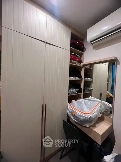 Modern bedroom with built-in wardrobe and air conditioning unit, featuring a sleek dressing area.
