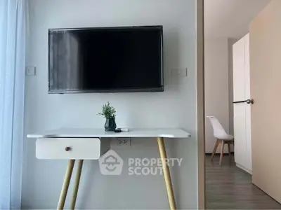 Modern study area with wall-mounted TV and sleek desk in stylish apartment.