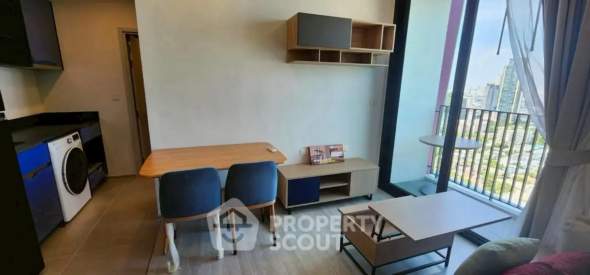 Modern living room with balcony and city view, featuring stylish furniture and a washing machine.