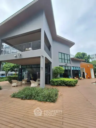Modern two-story building with spacious outdoor seating and lush greenery, perfect for relaxation and gatherings.