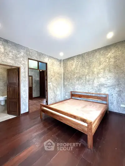 Spacious bedroom with wooden flooring and modern textured walls