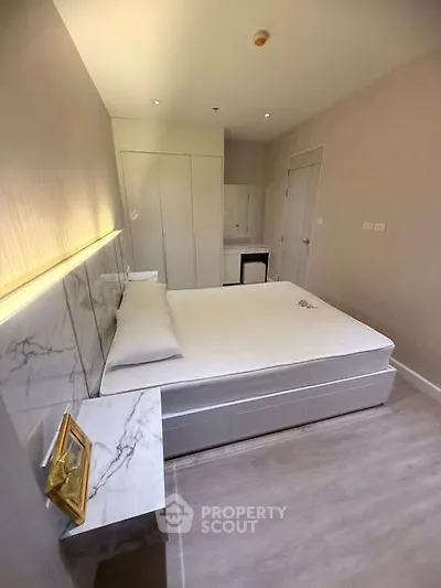 Modern bedroom with sleek design and marble accents, featuring a comfortable bed and ample storage space.