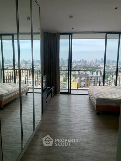 Spacious bedroom with floor-to-ceiling windows offering stunning city views.