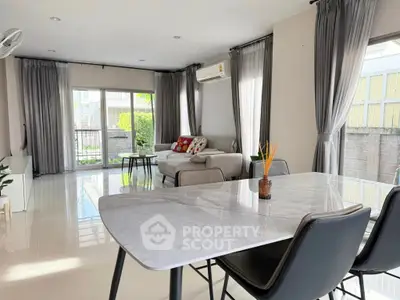 Spacious modern living room with elegant marble dining table and cozy seating area, flooded with natural light.
