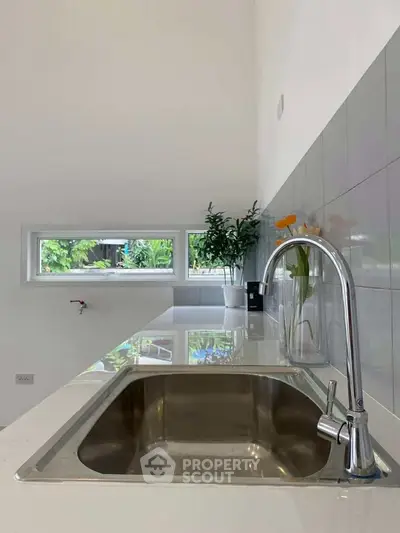 Modern kitchen with sleek sink and minimalist design, featuring a bright window view.