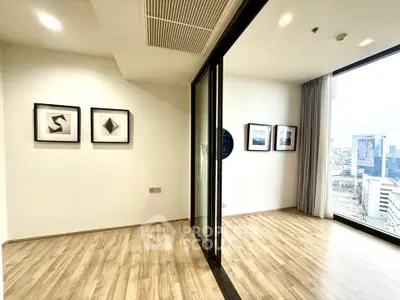 Modern apartment with wooden flooring and large windows offering city views, perfect for urban living.