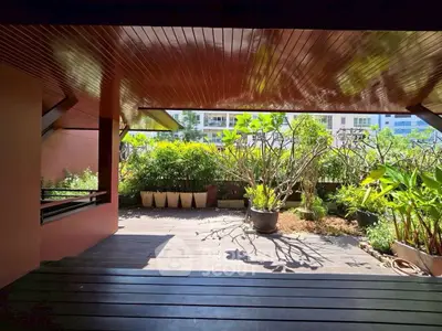 Spacious balcony with lush greenery and modern wooden ceiling, perfect for relaxation.