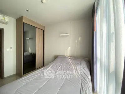 Bright and cozy bedroom with large window and modern wardrobe in a stylish apartment.