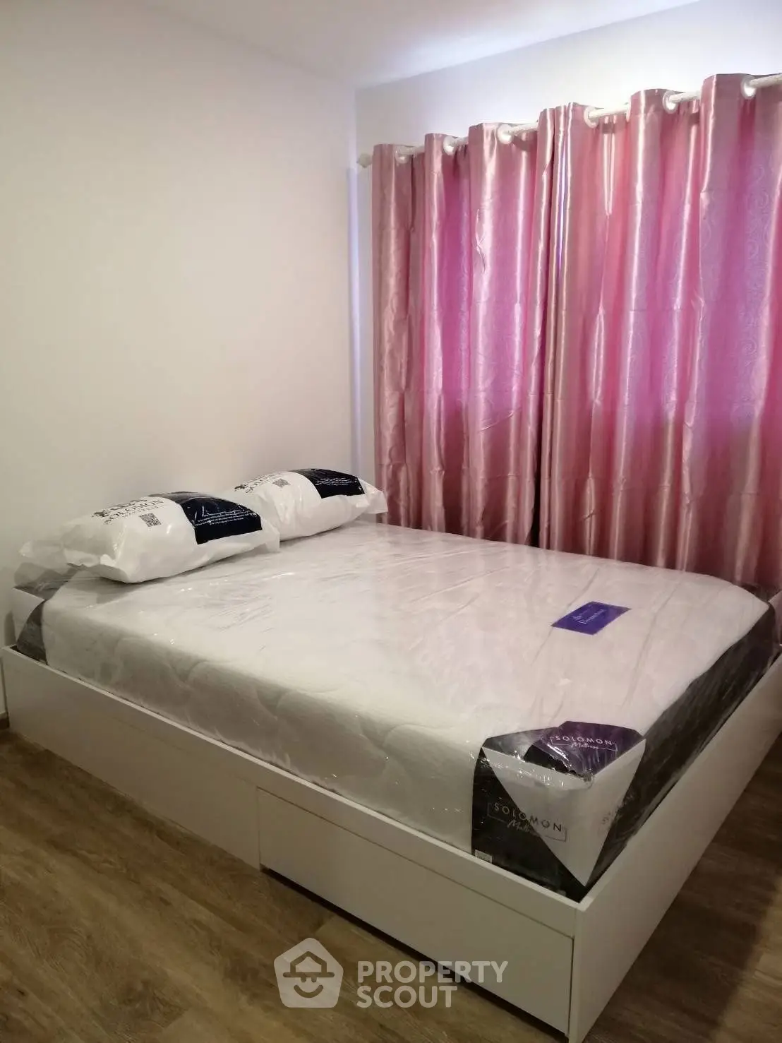 Cozy bedroom with elegant pink curtains and a neatly made bed, perfect for relaxation.