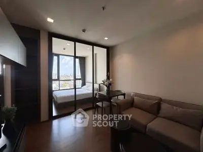 Modern living room with glass partition to bedroom, featuring cozy sofa and city view.