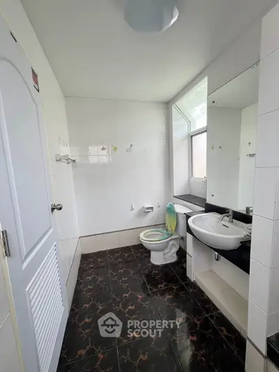 Modern bathroom with sleek black and white design, featuring a large mirror and natural light.