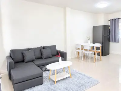 Modern living room with sleek gray sofa and dining area in open layout apartment.