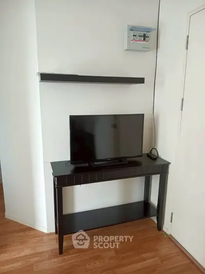 Modern living room with sleek black TV stand and wall-mounted shelf, showcasing minimalist design.