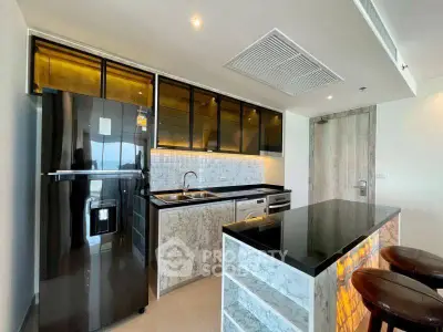 Modern kitchen with sleek black fridge and marble countertops in luxury apartment.
