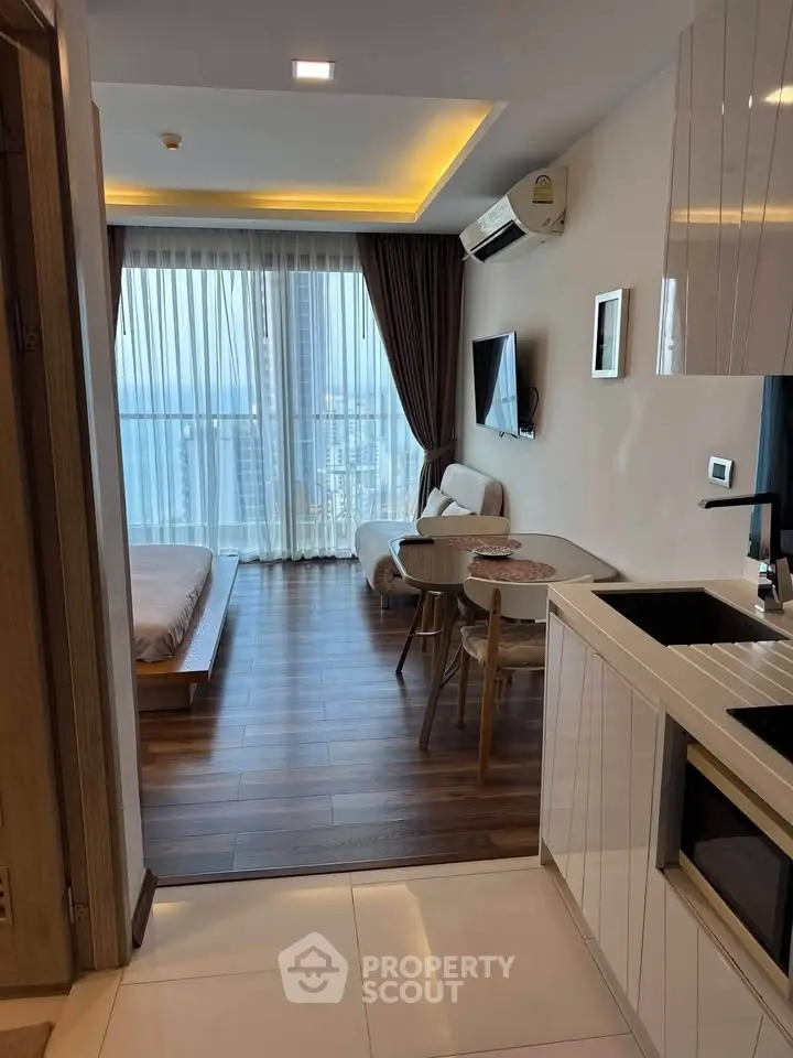 Modern studio apartment with open layout, featuring a cozy living area, sleek kitchen, and stunning city view.
