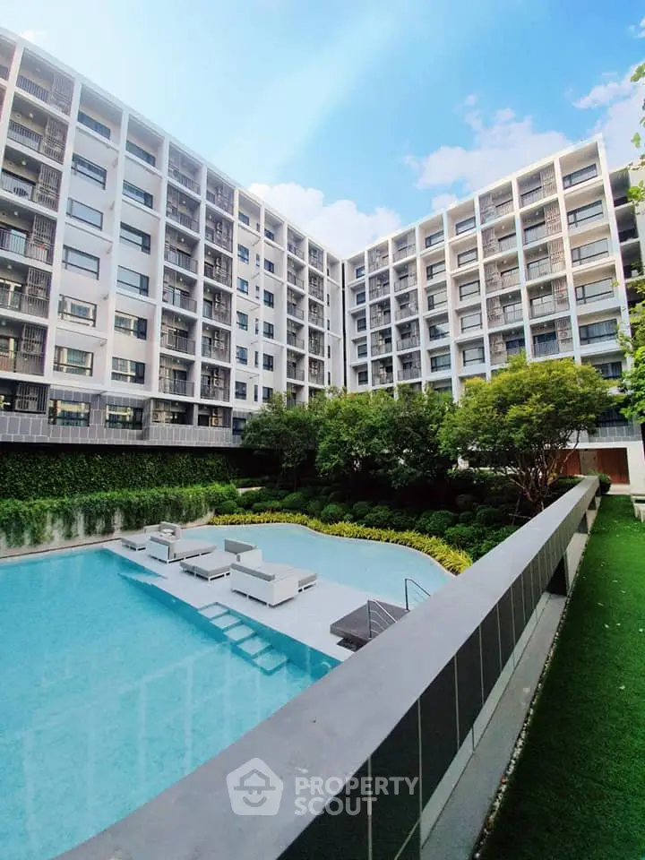 Modern residential building with pool and lush garden, perfect for urban living.