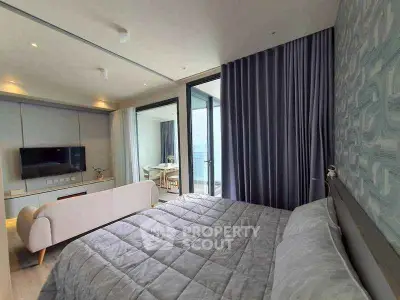 Luxurious bedroom with modern decor and large windows opening to a private balcony.