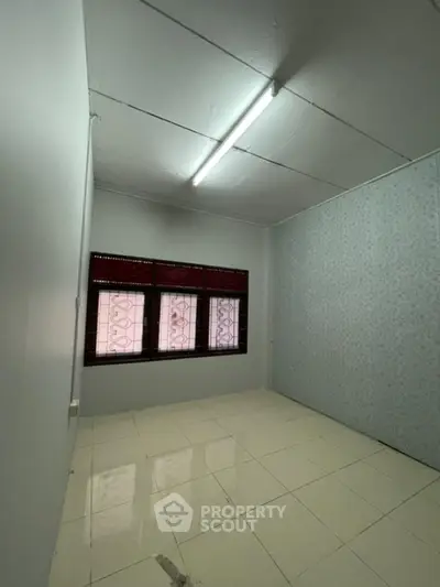 Spacious empty room with tiled floor and large window, ideal for customization.