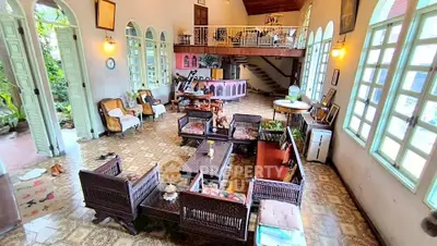 Spacious vintage living room with unique decor and high ceilings, featuring classic furniture and large windows.