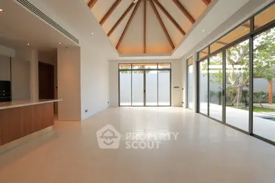 Spacious modern living room with high ceiling and large windows opening to garden.