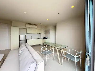 Modern open-plan living room with kitchen, featuring sleek furniture and natural light.