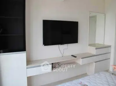 Modern bedroom with wall-mounted TV and sleek storage solutions.