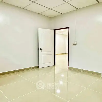 Spacious empty room with tiled flooring and white walls, ideal for customization.