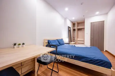 Modern bedroom with wooden flooring and stylish blue bedding