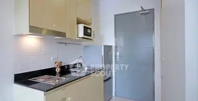 Compact modern kitchen with sleek cabinets and stainless steel appliances.
