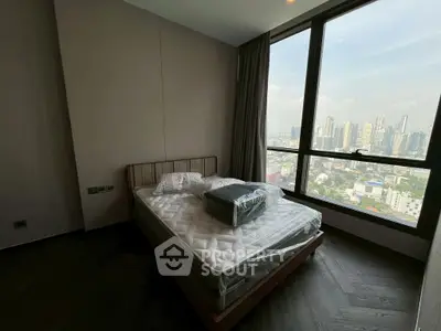 Modern bedroom with city view and large window in high-rise apartment