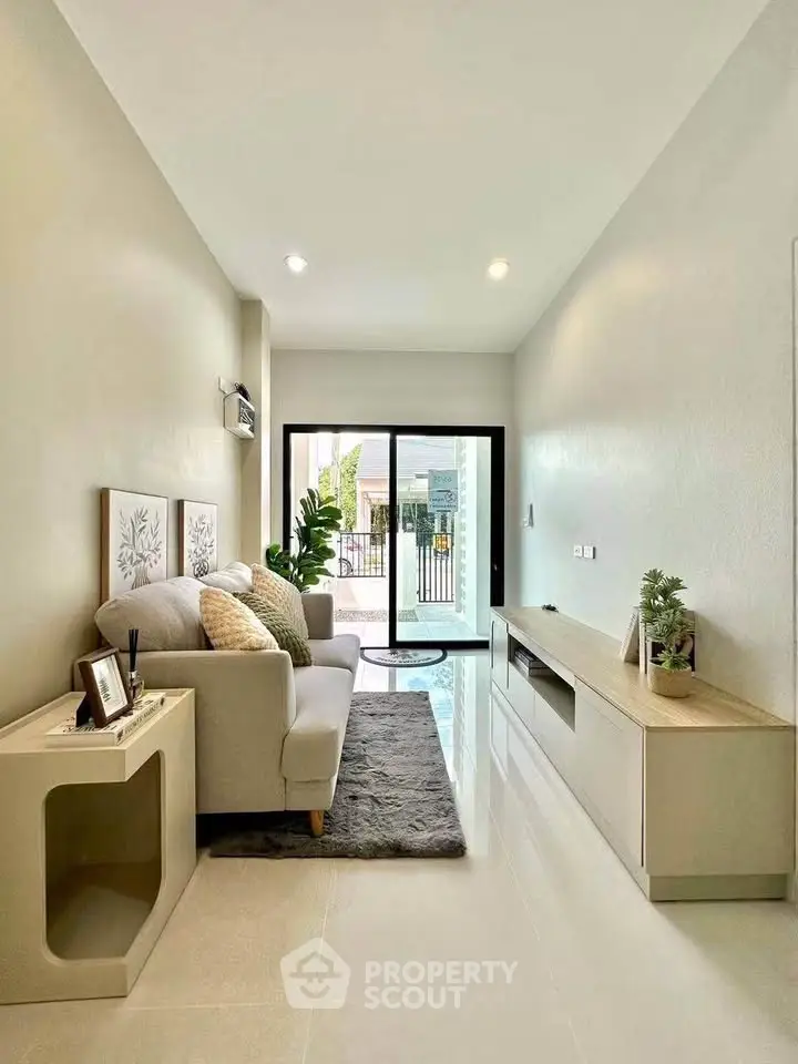 Modern living room with sleek furniture and large window offering natural light.