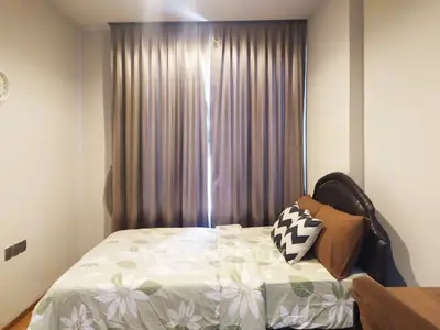 Cozy bedroom with floral bedding and elegant curtains in a modern apartment.