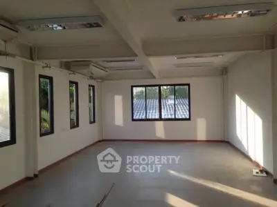 Spacious empty room with large windows and natural light, ideal for office or studio space.