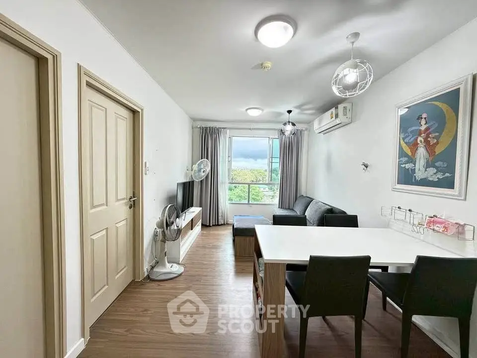 Modern living room with dining area, featuring sleek furniture and large window with scenic view.