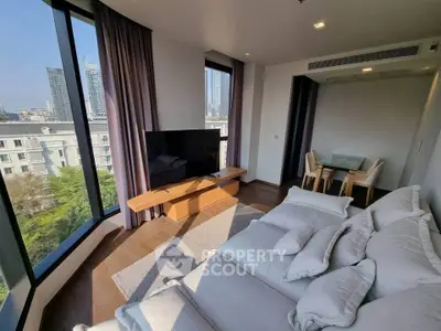 Spacious modern living room with large windows and city view, featuring a cozy sofa and sleek dining area.