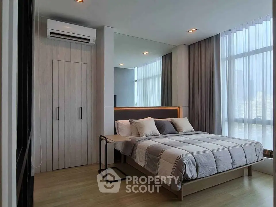 Modern bedroom with large windows and stylish decor in a high-rise apartment.