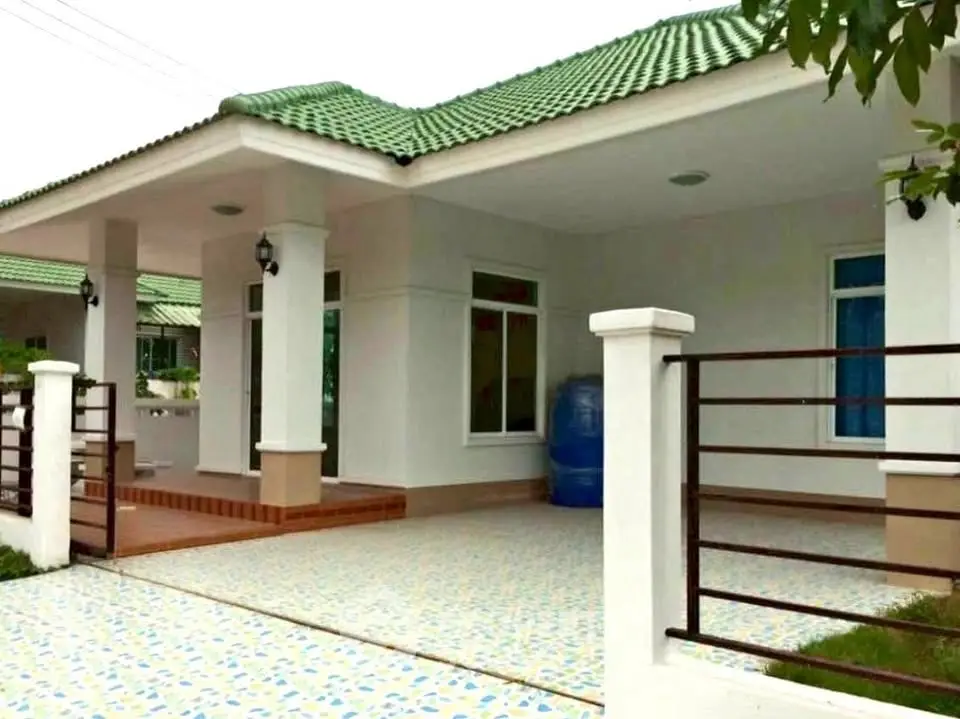 Charming single-story home with green roof and spacious tiled patio, perfect for family living.