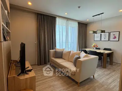 Modern living room with cozy sofa and dining area, featuring elegant decor and natural light.