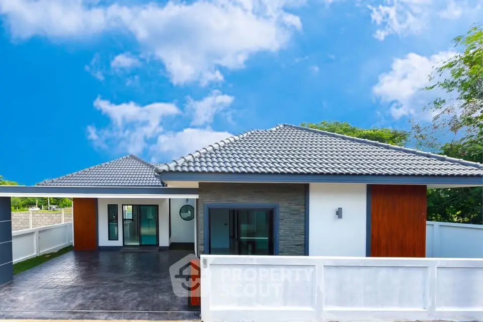 Modern single-story house with sleek design and spacious driveway under a clear blue sky.