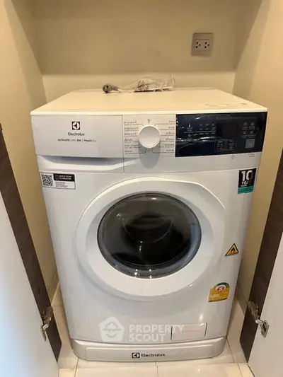 Modern Electrolux washing machine in a compact laundry space with open doors.